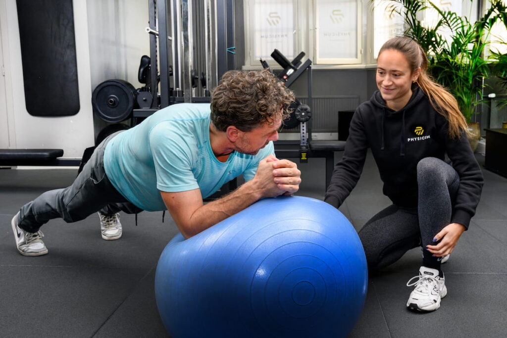 Personal trainer met cliënt en oefening op de bal tijdens training in de zaal
