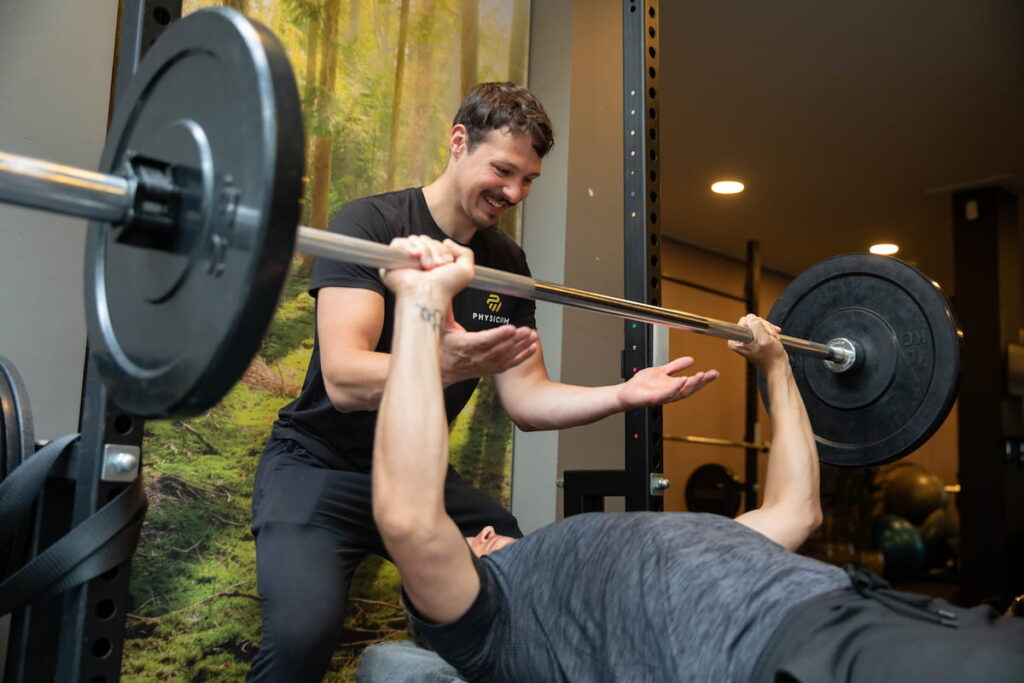 Personal trainer helpt cliënt met bankdrukken